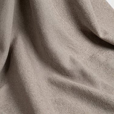 Heavy linen-weave fabric drape in soft taupe, showcasing tactile textile quality and precise seam stitching