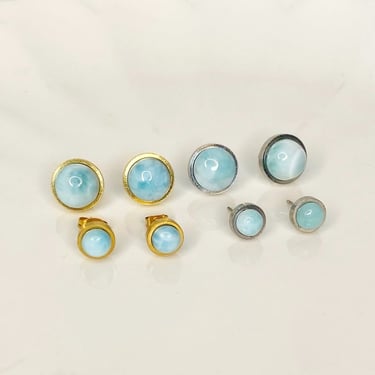 Aretes de chapa dorados y plateados con piedra Larimar sobre una superficie blanca.