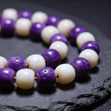 Macro close-up of hand-carved purple and white wampum beads on a dark slate surface, soft museum spotlighting highlighting the rich textures.