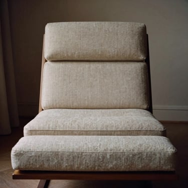 Tactile luxury textiles in neutral tones layered on a modern lounge chair, low-key natural light, medium format film