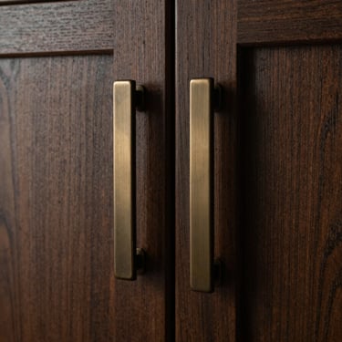Macro detail of bespoke brushed bronze hardware on dark oak cabinetry, moody shadows, medium format film