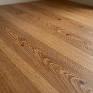 Close-up of warm engineered wood flooring, grain detail visible under soft directional light, grain pattern and warm tone prominent, no feet or furniture
