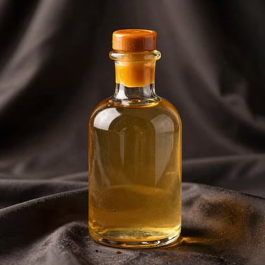 A heavy glass bottle with a saffron-tinted wax seal, resting on dark silk fabric, warm golden side-light.
