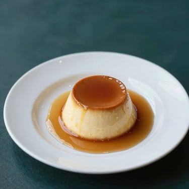 A perfect creamy caramel custard flan with dark caramel sauce on an elegant white plate, soft studio lighting