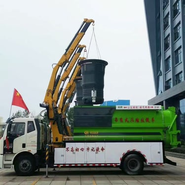 A knuckle boom truck crane lifting a large green and white container.