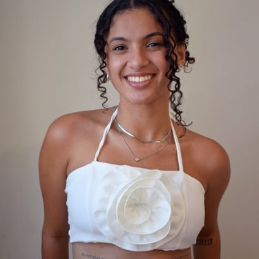 Uma mulher com blusa branca e cabelos cacheados presos no alto da cabeça