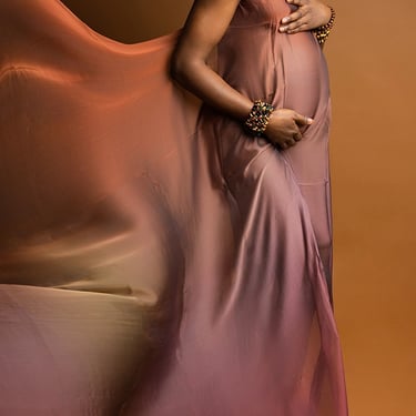 photographie de grossesse d'une femme de couleur sur fond brun portant un voile en robe brun irisé pour la mettre en valeur