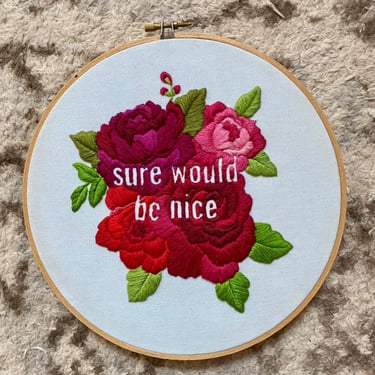 Pink and red embroidered flowers on a pale blue background with the words "Sure Would Be Nice"