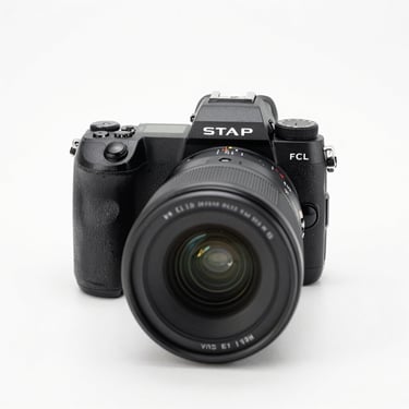 Sharp front view of a professional mirrorless camera, clean white studio backdrop, high-key lighting