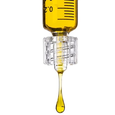 Close-up of a medical syringe dripping yellow liquid oil against a white background.