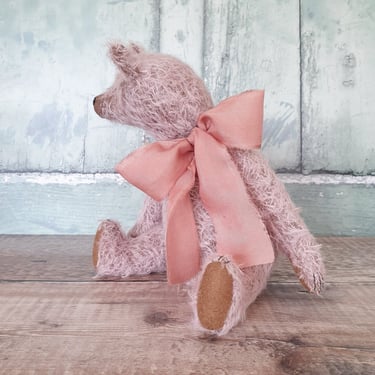 a pale pink teddy bear wearing a big pink bow