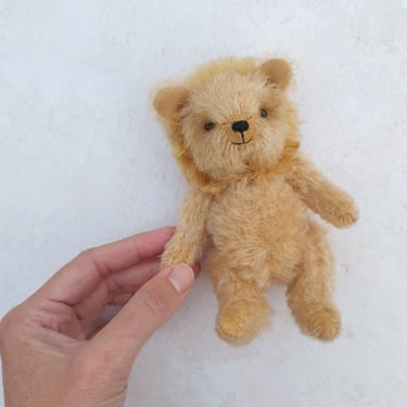 a tiny little handmade mohair lion whose paw is held by a human hand