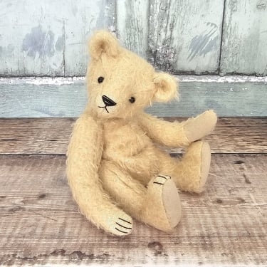 a little hand made teddy bear sitting on a table