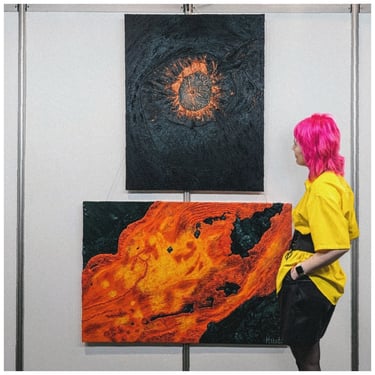 a woman in a yellow shirt is standing in front of two paintings