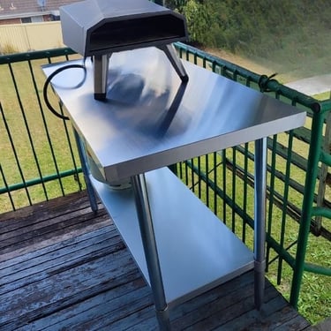 Table Hire: Stainless steel bench with pizza oven on a balcony, perfect for outdoor cooking.