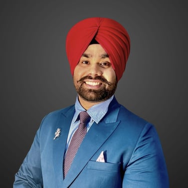 A smiling Amandeep Singh wearing a red turban and blue professional suit with a tie and lapel pin.