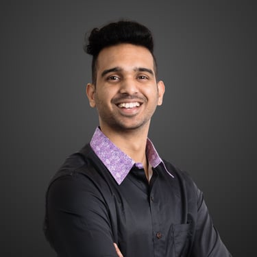 Clive Dsouza, a smiling young man in a black button-down shirt with a purple patterned collar.