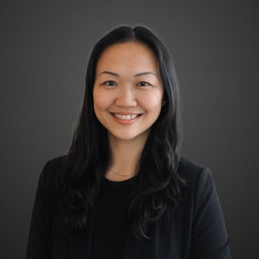 Professional headshot of a smiling Ka Ki Wood with long black hair wearing a black blazer.