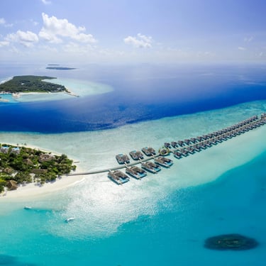 Aerial view of luxury overwater villas and tropical islands in the Maldives surrounded by turquoise ocean waters