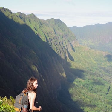 A female hiker preparing to take a photo of a fast valley surrounded by mountains. 