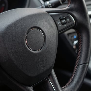 Macro shot of matte, steam-cleaned leather stitching on a premium steering wheel, perfectly clean with no artificial shine.