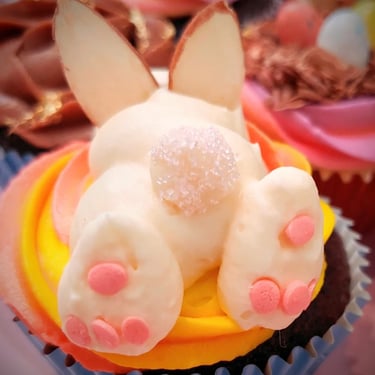 Easter bunny cupcake with almond ears and a sparkling sugar tail on yellow frosting.