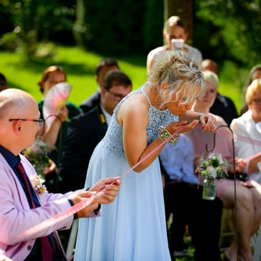 Hochzeitsgäste beteiligen sich an einem Ritual während einer freien Trauung im Freien.