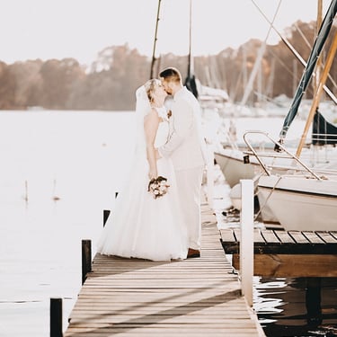 Brautpaar bei einem Hochzeitsshooting auf einem Steg am See mit Segelbooten im Hintergrund