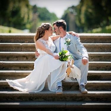 Romantisches Brautpaar sitzt auf einer Parktreppe – emotionale Hochzeitsfotografie im Freien.