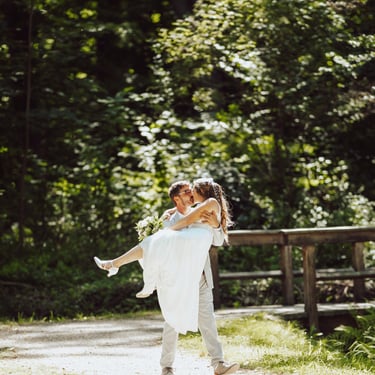 Bräutigam trägt die Braut im Wald, natürliche Hochzeitsreportage im Grünen