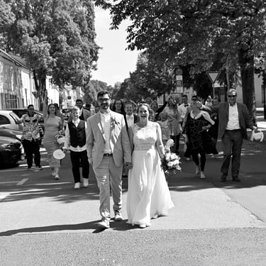 Auszug des Brautpaares nach der Trauung in Rheinsberg, begleitet von Hochzeitsgästen auf der Straße.