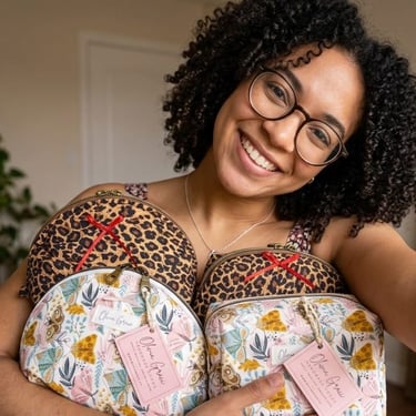 Smiling woman holding handmade leopard print and floral makeup bags by Olivia Grace.