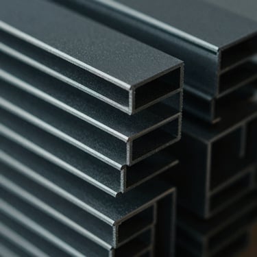 Extreme close-up of dark grey extruded PVC profiles stacked in geometric patterns under low-key dramatic side-lighting, cold metallic tones, 35mm