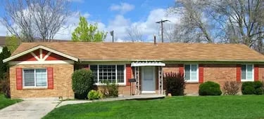 "Exterior view of a Boise student rental property featuring a brick facade, red accents, and professional landscaping."