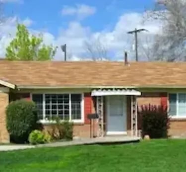 "Exterior view of a Boise student rental property featuring a brick facade, red accents, and professional landscaping."