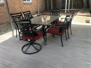 7-piece metal patio dining set with red cushions on a paved deck at off-campus student housing.