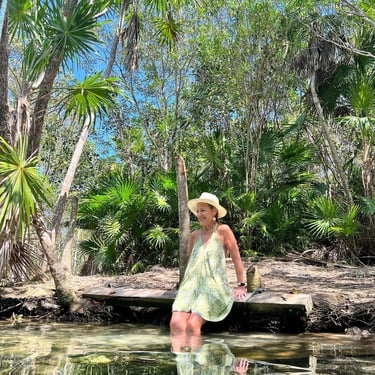 a woman in a dress and hat at a cenote at a retreat in Mexico