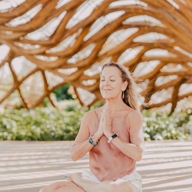 retreat in Mexico - a woman in a pink tank top and white shorts sitting on a wooden floor
