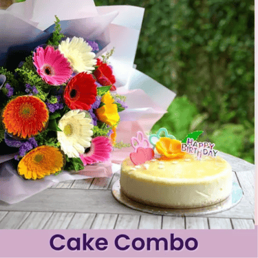 Birthday cheesecake with Happy Birthday topper next to a colorful gerbera daisy flower bouquet gift combo.