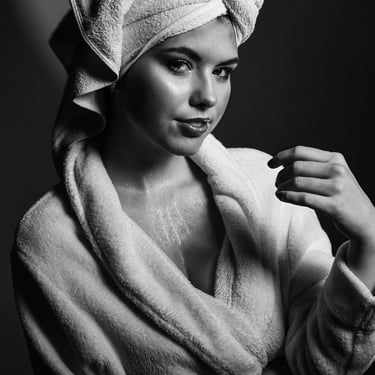 Schwarz-Weiß-Porträt einer jungen Frau in Bademantel und Handtuchturban, die verführerisch blickt.