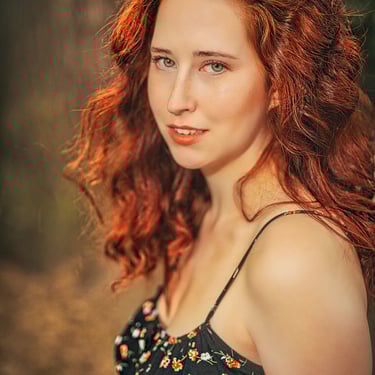 Nahaufnahme einer jungen Frau mit roten Locken und grünen Augen im schwarzen Blumenkleid – emotionales Portrait von LensandLo