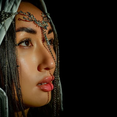 Fine-Art-Portrait einer Frau mit ornamentaler Kopfbedeckung und seitlichem Licht vor schwarzem Hintergrund.