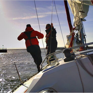 Équipage naviguant à l'avant du voilier, avec vue sur la mer