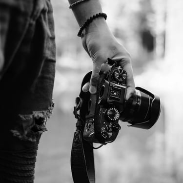 Street photographer carrying a DSLR camera in black and white
