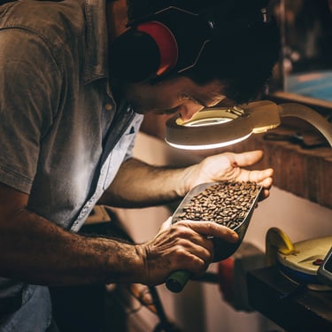 A coffee roaster checking freshly roasted coffee beans under light to check for evenness and level of roast