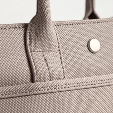 Detail close-up The Serenity Tote, menyorot tekstur kanvas poliester SIGNIFO, jahitan, dan aksesoris yang digunakan.