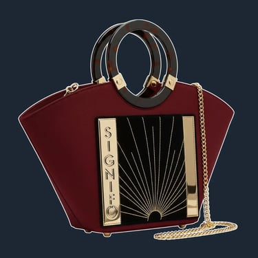A highly structured, fan-shaped tote with a rigid frame and elegant, geometric lines inspired by Art Deco architecture.