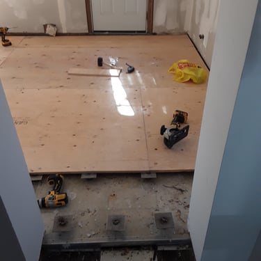 Floor leveling and plywood subfloor installation in entryway renovation using adjustable pedestal supports