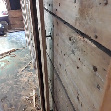 Wall reinforcement in progress with plywood panels and anchor bolts during interior renovation of an older home