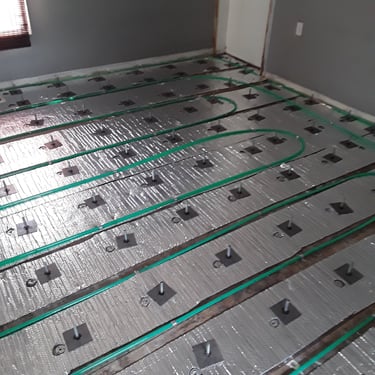 Radiant floor heating system installation over insulation panels with adjustable pedestals for subfloor leveling
